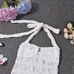 Close-up of white lace halter top with detailed crochet patterns and delicate hollow-out fabric