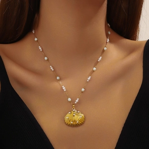 Gold shell pendant necklace with pearls on a model neck for beach fashion looks