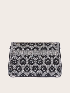 Macro detail of black evening bag with sunflower pattern rhinestones and silver chain