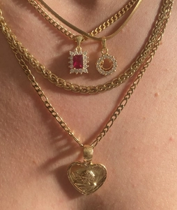 Close-up of 18k gold plated layered chains with heart relief and red gemstone pendants