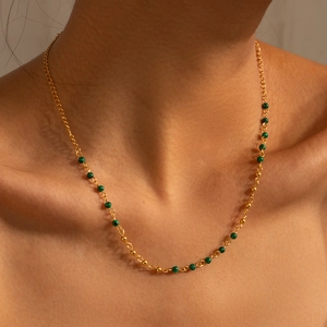 Detailed close-up of 18K gold-plated necklace with turquoise beads on woman neck