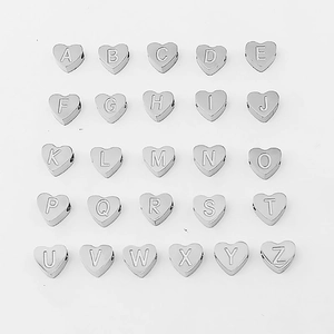 Macro view of twenty-six silver heart-shaped alphabet pendants on a white background