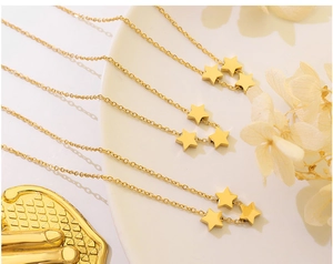 Détail de trois pendentifs étoiles dorées polies sur des chaînes fines au style luxueux