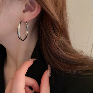 Close-up of elegant silver hoop earring worn by model, showing sleek metallic finish