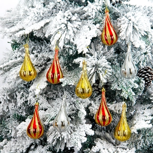 Festive teardrop Christmas ornaments in red, gold, and silver on a snowy tree branch