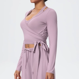 Detail of cross-wrap tie waist design on long-sleeve yoga top in smoky purple fabric