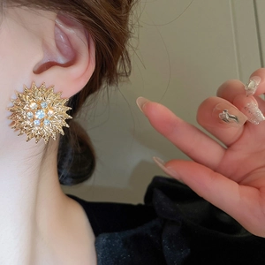 Gros plan d'une boucle d'oreille tournesol dorée avec strass scintillants sur le modèle
