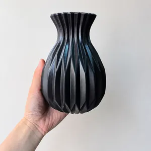 Detail einer schwarzen geometrischen Blumenvase mit Diamantfacetten in der Hand