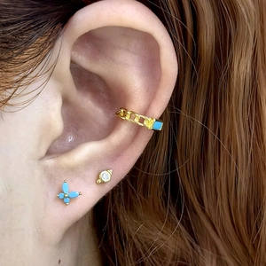 Close-up of gold chain ear cuff and blue crystal butterfly stud earrings set on ear