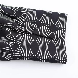 Detailed view of the buttoned cuff on a women's blouse with white geometric fan patterns