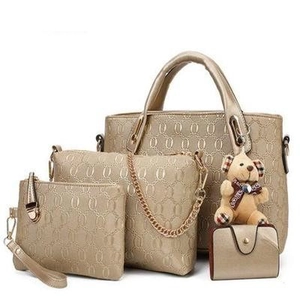 Detail view of champagne gold 4-piece handbag set featuring embossed rings and teddy bear charm
