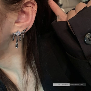 Close-up of liquid silver tassel earrings with square zircon on a model in a black suit