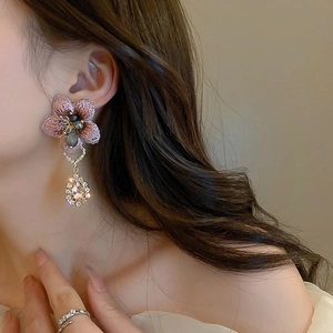 Orecchini asimmetrici a fiori rosa con cristalli a goccia su modella per un look di lusso