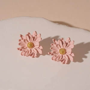 Close-up of pink flower stud earrings with golden stamens and matte textured petals