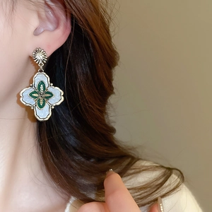 Gros plan de boucles d'oreilles fleur vintage avec pétales verts et détails dorés