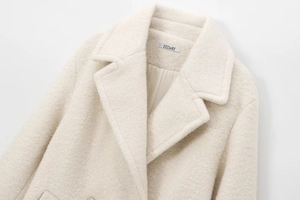 Detail of white double-breasted wool coat showing lapel texture and brand label