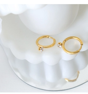 Macro shot of gold hoop earrings featuring sparkling heart-shaped zircon drop detail