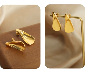 Detailed view of golden irregular teardrop earrings on wood and metal display stands