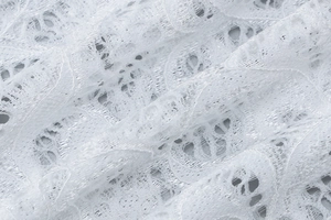 Gros plan sur un tissu en dentelle blanche avec motifs floraux ajourés complexes