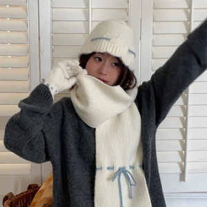 Detail of cream knitted scarf and gloves set with elegant blue stitching decoration