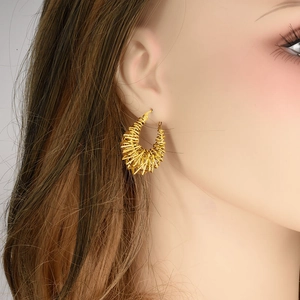 Golden 304 stainless steel hoop earrings with bird nest textured design worn by a model