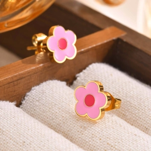 Macro view of pink flower stud earrings with gold plating on a soft white fabric