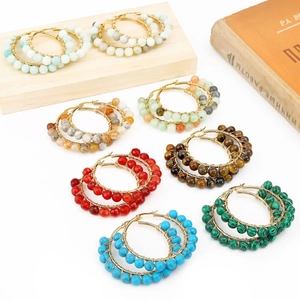 Detailed close-up of handmade gold wire-wrapped hoop earrings with colorful natural stones