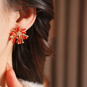 Détail de la boucle d'oreille fleur feu d'artifice en émail rouge sur le modèle