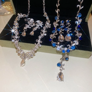 Macro detail of diamond-studded flower pendant necklaces and earrings in a gift box