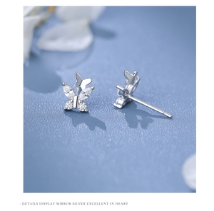 Macro shot of silver butterfly stud earrings with sparkling zircon stones in mirror finish