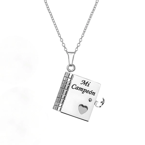 Detail of silver book-shaped pendant with Mi Campeón engraving and heart cutout