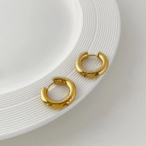 Close-up of thick 18K gold plated stainless steel hoop earrings on a white textured tray