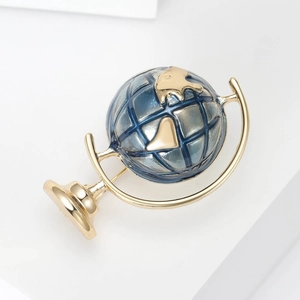 Detailed view of globe brooch featuring gold metal frame and blue enamel sphere detail