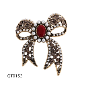 Vintage gold bow brooch with brown rhinestones, white pearls and a red center stone