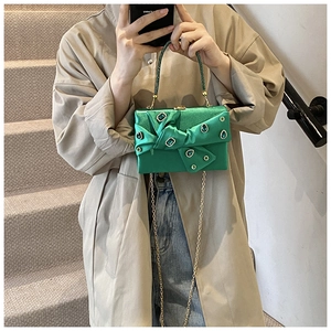 Green satin clutch bag with bow decoration and beaded handle shown in hand