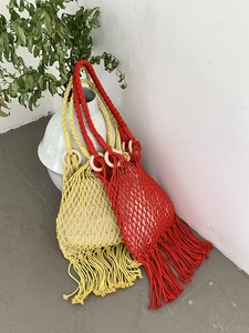 Detail of red and yellow hand-woven tote bags with wooden handles and long fringe tassels