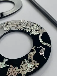 Detail of handcrafted shell inlay hairpin featuring traditional pine and crane patterns