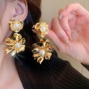 Boucles d'oreilles fleuries dorées avec perles présentées sur un mannequin féminin