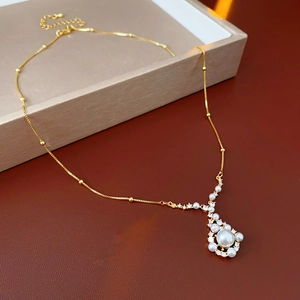 Close-up of gold-plated pendant necklace with pearl and zircon inlay on jewelry box