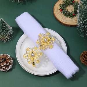 Detailed view of gold snowflake napkin rings with rhinestones and pearl on table