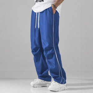 Deep blue baggy sports pants with white side stripes and drawstring waist in a studio shot