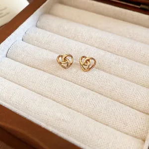 Minimalist gold heart stud earrings with knot design displayed in a premium jewelry box