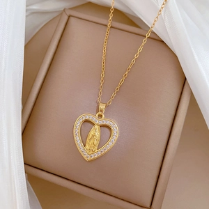 Detailed view of gold heart pendant with saint relief and pavé-set crystals