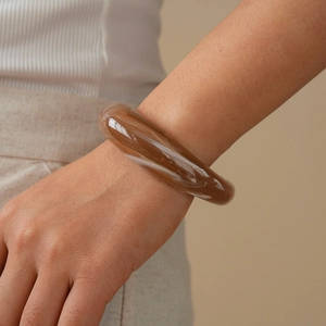 Macro detail of acrylic marble cuff bracelet showing translucent amber and white swirl texture