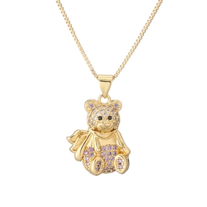 Close-up of golden teddy bear pendant with purple and pink gemstones on box chain