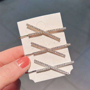 Macro detail of three-piece set of X-shaped alloy hair clips with sparkling rhinestones