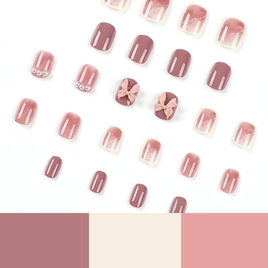 Pink and purple gradient press-on nails with 3D bows, pearls, and glossy marble texture