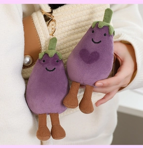 Cute plush eggplant keychain with cartoon face and heart detail on a woven bag