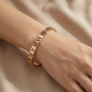 Close-up of rose gold titanium steel bangle with Roman numeral engravings on a model