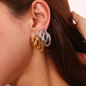 Primer plano de pendientes de aros entrelazados de oro y plata en la oreja de una modelo